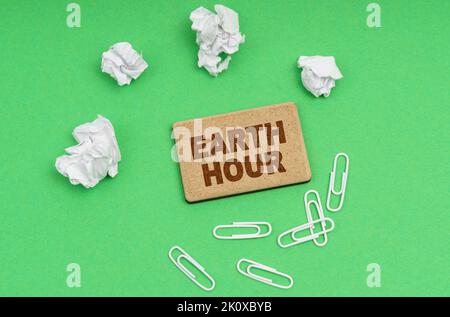 Concept d'écologie. Sur fond vert, papier froissé, trombones et un signe avec l'inscription « Earth Hour » Banque D'Images