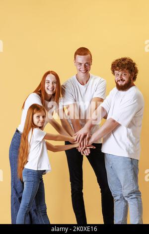 Soins et soutien. Groupe d'âges différents redhead personnes tenant leurs mains et riant isolé sur fond jaune. Émotions, amitié Banque D'Images