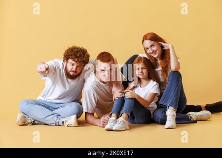 Frères et sœurs. Famille amicale, tête rouge jeunes hommes, femme et enfant portant des vêtements décontractés passer du temps ensemble à la séance photo en studio. Banque D'Images