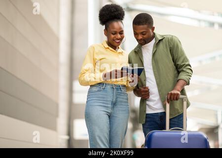 Joyeux couple de touristes afro-américains voyageant ensemble tenant des passeports à l'extérieur Banque D'Images