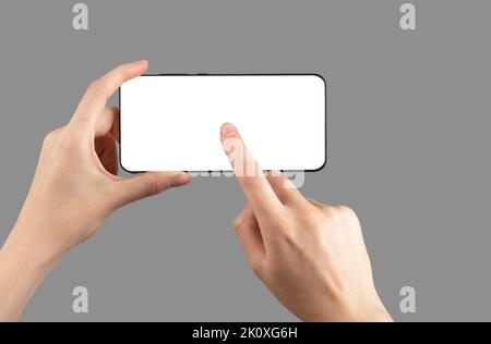 Mains tenant la maquette du téléphone en position horizontale. Femme en cliquant, en appuyant sur le bouton de lecture pour regarder la vidéo. Modèle de smartphone avec écran vide. Hin Banque D'Images