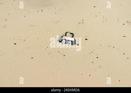Un sac à main en plastique jeté s'est lavé et à moitié enterré sur le sable Banque D'Images