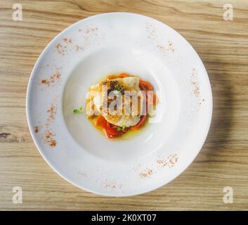 Délicieux cabillaud cuit au four avec poivre rouge rôti sur une table en bois. Banque D'Images