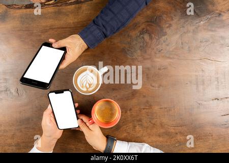 Deux modèles de smartphone, photo de la vue du dessus de deux modèles de smartphone. Couple assis sur la table en bois ignorant l'un l'autre en utilisant ses propres téléphones mobiles. Banque D'Images