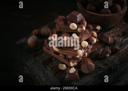Pile de chocolat au lait de noisette et de noix sur fond sombre Banque D'Images