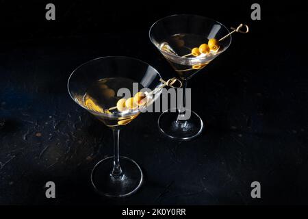 Martini, deux verres aux olives épicées, sur fond noir. Boisson froide alcoolisée Banque D'Images