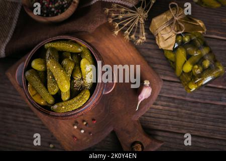 Cornichons marinés avec aneth et ail dans un pot en verre sur une table en bois sombre Banque D'Images