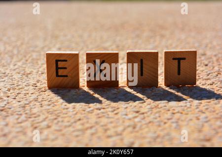 Sortie, mot en lettres de l'alphabet en bois rétro-éclairé et isolé sur fond texturé Banque D'Images