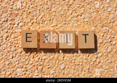 Sortie, mot en lettres de l'alphabet de bois isolées sur fond de pierre texturée Banque D'Images