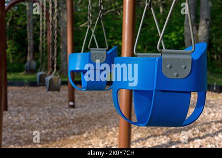Aire de jeux vide avec balançoires et sièges pour bébé sous la lumière du matin. Banque D'Images