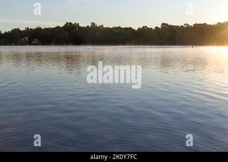 Brouillard qui s'élève sur le lac Swan dans le Maine au début de l'automne avec un rivage éloigné. Banque D'Images