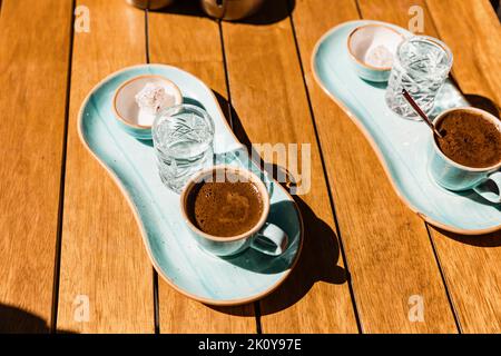 une tasse de café turc noir chaud dans une tasse bleue servie avec un verre d'eau et de sucre Banque D'Images