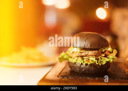 Gros plan d'un hamburger juteux avec du délicieux Cutlet et de la laitue entre des petits pains rôtis au restaurant. Vue avant Burger avec légumes et viande. Juteux Banque D'Images