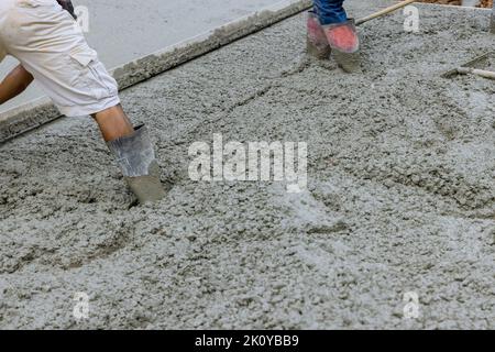 Pendant le versement de voies d'accès en béton, un travailleur est vu couler du béton pour le stationnement Banque D'Images