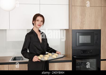 Jeune belle femme préparant des croissants dans la nouvelle cuisine moderne Banque D'Images