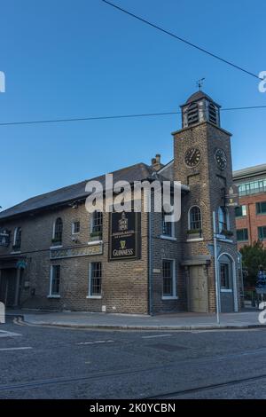 Vue sur le bâtiment en briques grises du bar et restaurant Harbour Master avec une tour d'horloge à Dublin, Irlande. Banque D'Images