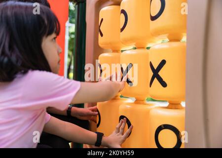 Enfant fille jouant au jeu TIC-tac-TOE au terrain de jeu dans le parc. Banque D'Images