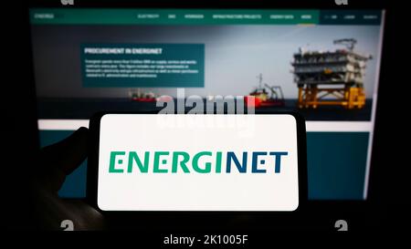 Personne tenant un smartphone avec le logo de l'opérateur danois du système de transmission Energinet à l'écran devant le site Web. Mise au point sur l'affichage du téléphone. Banque D'Images