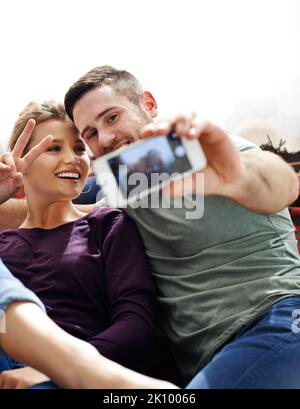 Nous adorons les selfies. Un jeune couple prend un selfie ensemble tout en se relaxant à la maison. Banque D'Images