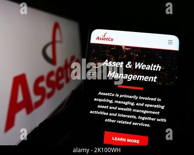 Personne tenant un téléphone portable avec la page Web de la société britannique de services financiers AssetCo plc à l'écran avec logo. Concentrez-vous sur le centre de l'écran du téléphone. Banque D'Images
