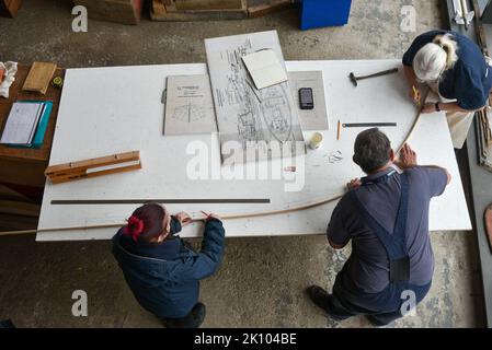 Construction navale et réparations à l'intérieur de la Boathouse numéro 4, chantier naval historique de Portsmouth. Le personnel travaille sur des plans sur une table en bois. Banque D'Images