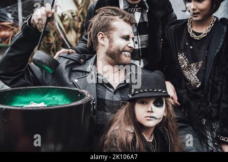 Famille effrayante, mère, père, filles célébrant halloween. Chou-fleur de potion.terrifiant crâne noir maquillage demi-visage, costumes de sorcière, image élégante Banque D'Images