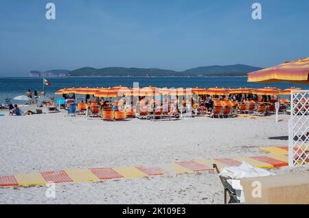 Parasols orange colorés sur la plage Spiaggia del Lido di Alghero d'Alghero, Sardaigne, Italie avec les falaises de Capo Caccia au loin Banque D'Images