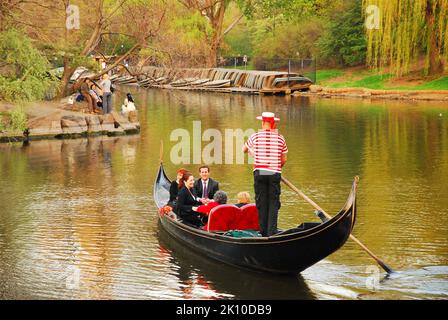 Un gondolier vénitien dirige une télécabine de l'autre côté du lac dans le parc central de New York, offrant un cadre romantique aux deux couples à bord Banque D'Images