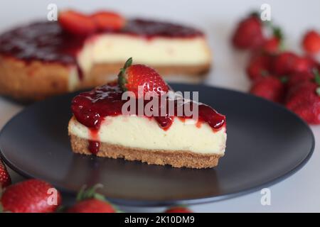 Tranche de gâteau au fromage fraise. Gâteau au fromage soyeux doux et crémeux recouvert d'une sauce aux fraises maison. Prendre avec des fraises fraîches autour Banque D'Images