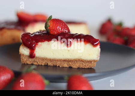 Tranche de gâteau au fromage fraise. Gâteau au fromage soyeux doux et crémeux recouvert d'une sauce aux fraises maison. Prendre avec des fraises fraîches autour Banque D'Images