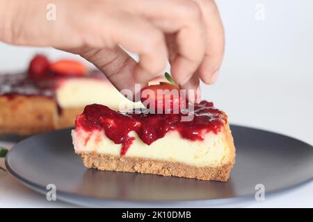 Tranche de gâteau au fromage fraise. Gâteau au fromage soyeux doux et crémeux recouvert d'une sauce aux fraises maison. Prendre avec des fraises fraîches autour Banque D'Images