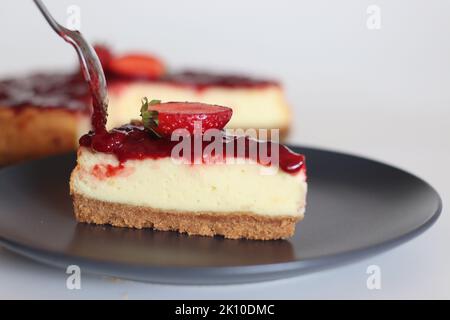 Tranche de gâteau au fromage fraise. Gâteau au fromage soyeux doux et crémeux recouvert d'une sauce aux fraises maison. Prendre avec des fraises fraîches autour Banque D'Images