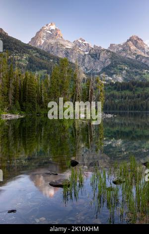 Un reflet parfaitement clair reflétant le Grand Teton et les montagnes Teton dans les eaux calmes du lac Taggart au lever du soleil. Grand Teton National Pa Banque D'Images