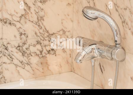 Robinets de température et de débit d'eau en acier inoxydable dans le coin d'une salle de bains en marbre Banque D'Images