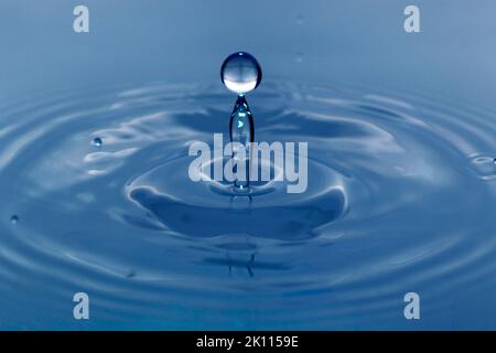 Une goutte tombe dans l'eau et crée de grandes formes Banque D'Images