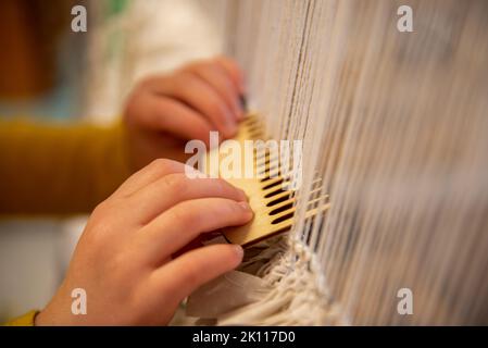 Enfant travaillant sur le métier à tisser gros plan des mains et peigne du métier à tisser Banque D'Images