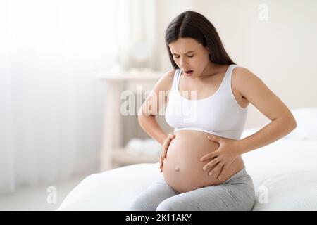 Femme enceinte souffrant de douleurs abdominales à la maison, espace de copie Banque D'Images