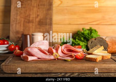 Planche avec jambon savoureux et craquelins sur une table en bois Banque D'Images