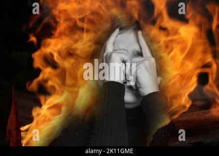 Défocation hurlant, haineux, fureur. Pleurer une femme en colère émotionnelle criant sur fond de flamme. Émotif, jeune visage. La femme stressée crie avec le feu et Banque D'Images