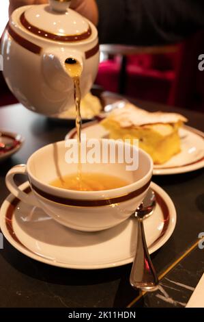 Temps du thé en Angleterre, verser du thé noir earl Grey avec bergamote dans une tasse, thé dînatoire servi café à Londres, gros plan Banque D'Images