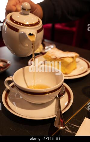 Temps du thé en Angleterre, verser du thé noir earl Grey avec bergamote dans une tasse, thé dînatoire servi café à Londres, gros plan Banque D'Images