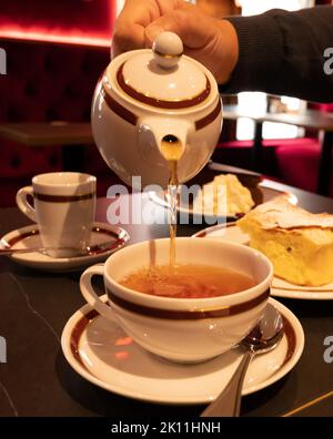 Temps du thé en Angleterre, verser du thé noir earl Grey avec bergamote dans une tasse, thé dînatoire servi café à Londres, gros plan Banque D'Images