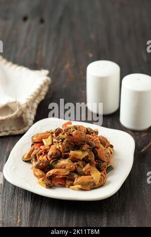 Tumis Kerang ou Oseng Kerang, Oyster frits au Chili, à l'ail, à l'oignon rouge et à d'autres épices. Sur une table en bois Banque D'Images