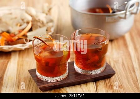 Deux verres de Wedang Uwuh, boisson chaude traditionnelle de Yogyakarta. Fait avec différentes épices. Servi sur un verre avec du sucre de roche. Sur une table en bois Banque D'Images