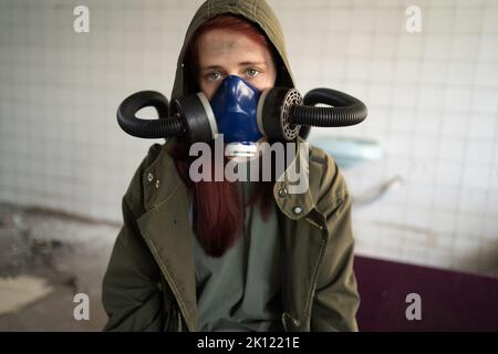 Post apocalypse femme survivante. Femme en masque à gaz portrait en gros plan dans la zone de guerre apocalyptique a abandonné la construction sur le fond. Copier l'espace Banque D'Images