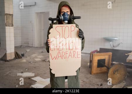 Photo d'une femme militaire dans un masque à gaz avec bannière dit arrêter la guerre chimique, apocalypse, armes nucléaires, explosion atomique d'une station, chimique a Banque D'Images