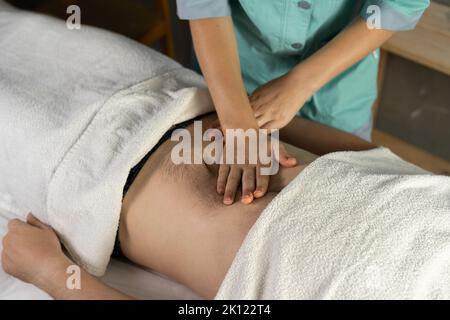 La masseuse féminine fait un massage viscéral des organes internes à travers l'estomac à un jeune homme dans une salle de spa. Banque D'Images