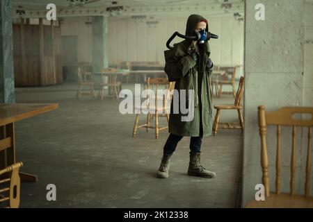 Femme post-apocalyptique dans un masque à oxygène ou un masque respiratoire dans un bâtiment, survivante d'une catastrophe environnementale et de la pollution de l'air Banque D'Images