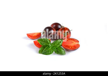 Basilic vert italien frais et rouge avec tomates entières et coupées sur fond blanc. Banque D'Images