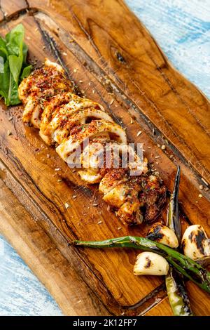 Calamars grillé épicé au poivre vert et à l'ail sur une table de service en bois Banque D'Images